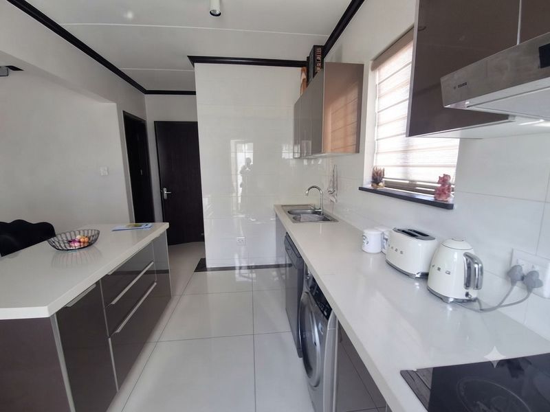 Modern kitchen featuring sleek cabinetry, stone countertops, integrated appliances, and high-gloss tiled flooring, offering a clean and functional workspace.