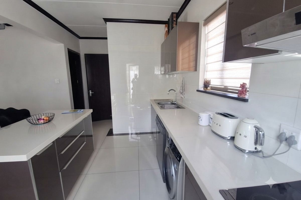 Modern kitchen featuring sleek cabinetry, stone countertops, integrated appliances, and high-gloss tiled flooring, offering a clean and functional workspace.