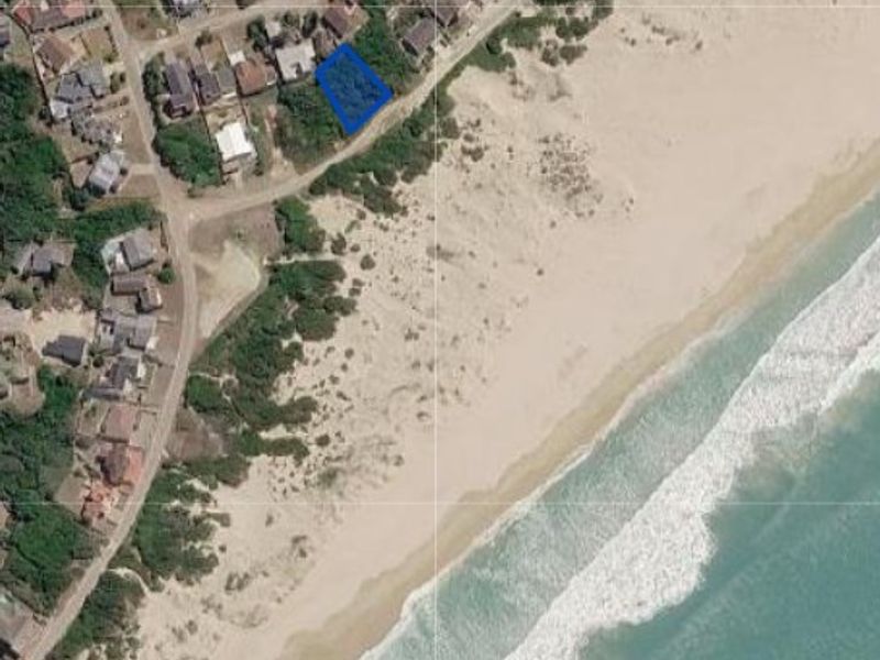 Aerial view of a vacant residential plot situated in a prime coastal location with direct proximity to the beach.