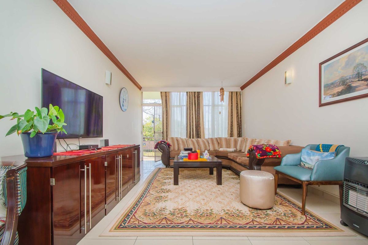 A spacious living room featuring tiled flooring, crown molding, and direct access to an outdoor patio area through a sliding glass door.