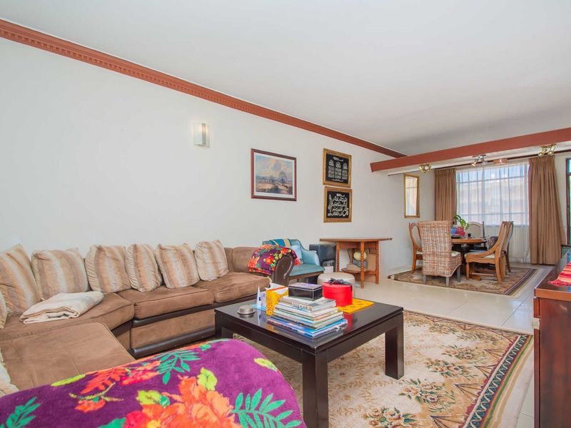 Spacious open-plan living and dining area featuring tiled flooring and crown molding, providing a versatile layout for comfortable daily living.