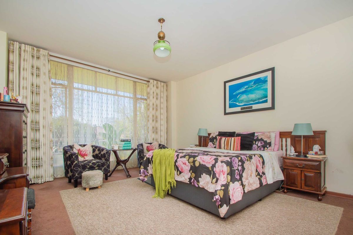 A spacious bedroom featuring large windows that provide ample natural light, neutral wall finishes, and carpeted flooring.