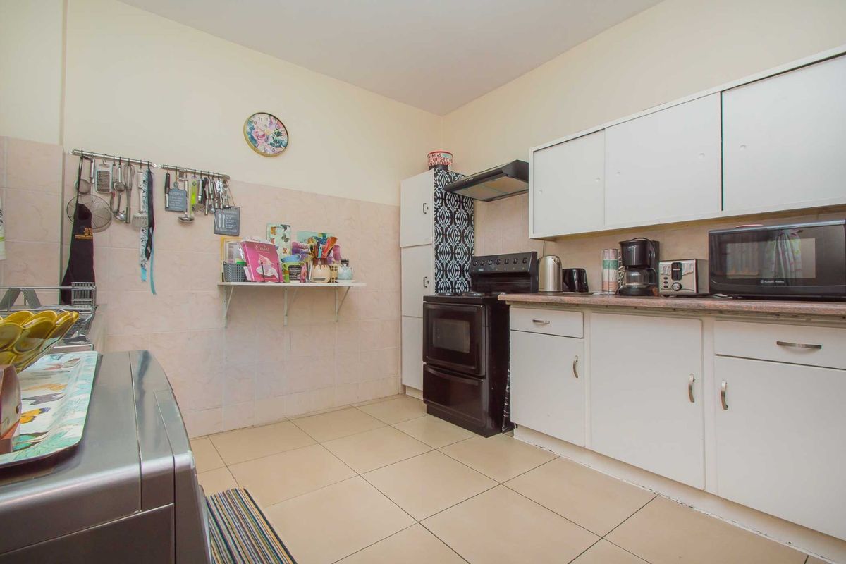 A functional kitchen featuring tiled flooring, a tiled backsplash, built-in cabinetry, and an extractor fan, offering a practical layout for daily cooking needs.