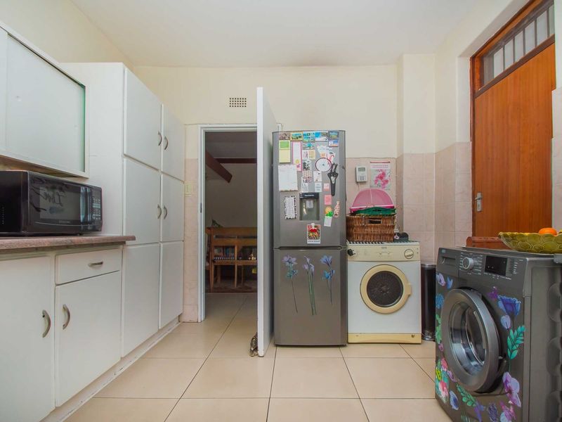 A functional kitchen featuring built-in white cabinetry, tiled flooring, and tiled splashbacks, providing a practical layout for daily use.