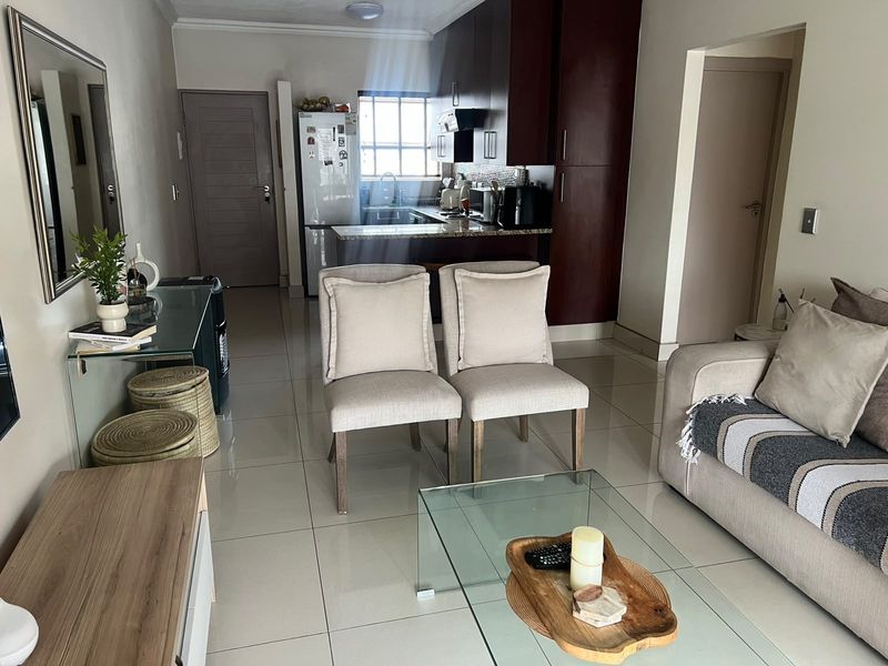 Open plan living area featuring a modern kitchen with dark cabinetry, granite countertops, and tiled flooring throughout the combined space.