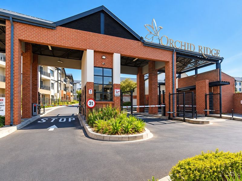 The secure entrance gatehouse of Orchid Ridge apartment complex, featuring brick architecture, boom gate access, and well-maintained landscaped surroundings.
