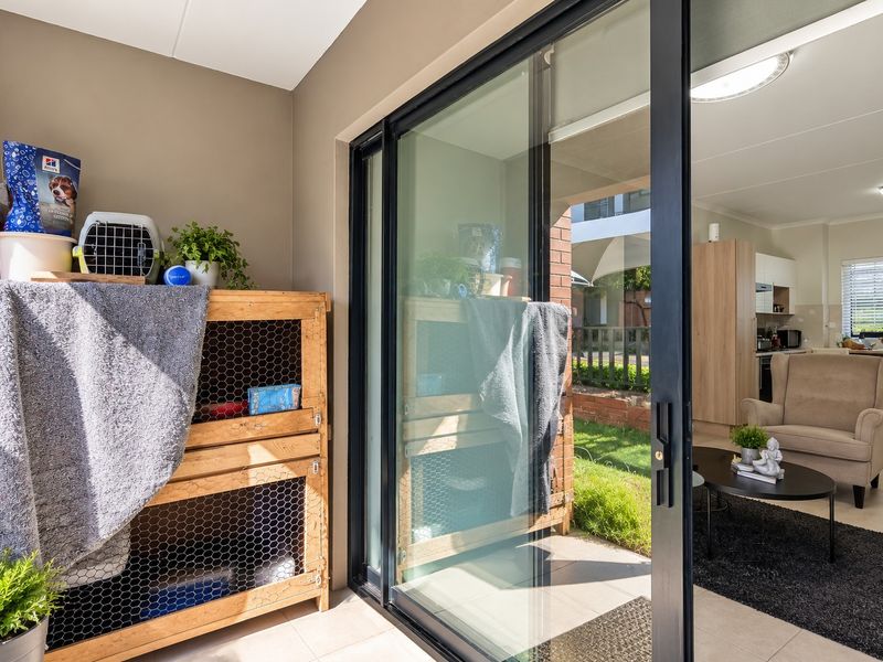 A covered patio area featuring tiled flooring and a large sliding glass door providing seamless access to the open-plan living space.