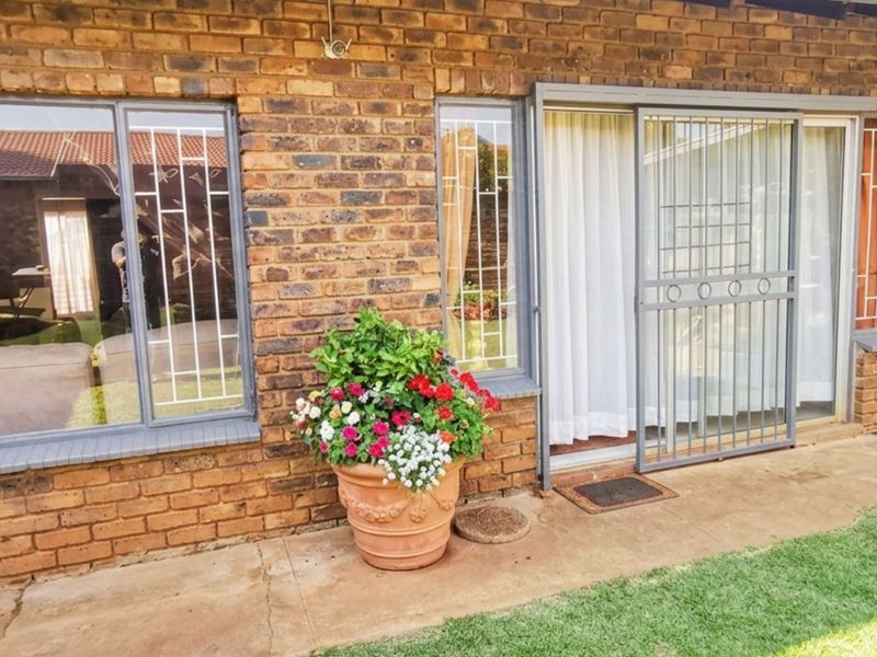Rear exterior view of the house featuring face brick walls, sliding glass doors with security gates, and a concrete patio area.