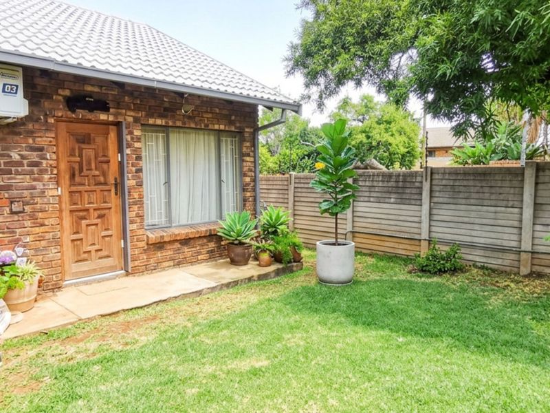 A private rear garden featuring a face brick exterior, paved walkway, and secure precast concrete boundary wall, providing a low-maintenance outdoor space.