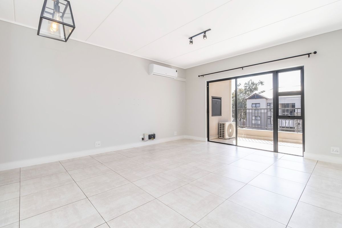 Bright and spacious open-plan living area featuring neutral tiled flooring, modern lighting, and direct access to a private balcony through sliding glass doors.