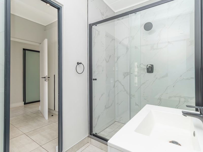 Modern bathroom featuring a walk-in shower with glass enclosure, black fixtures, and elegant marble-look wall tiles.