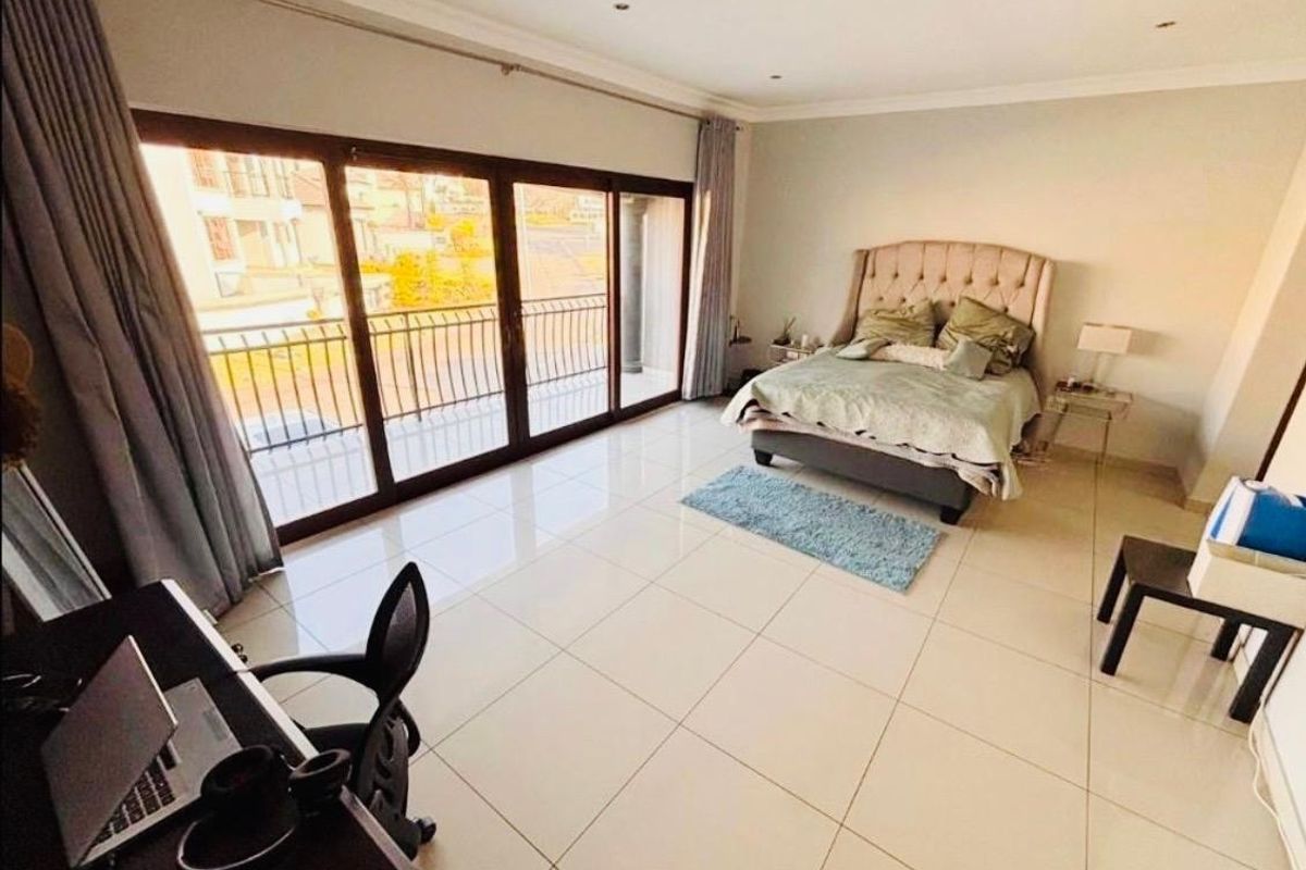 Spacious bedroom featuring large sliding glass doors leading to a balcony, neutral tiled flooring, and recessed ceiling lighting.