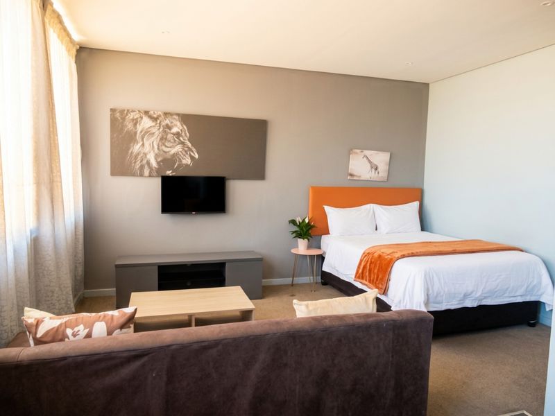 A well-maintained bedroom featuring neutral wall tones, recessed lighting, and carpeted flooring, providing a comfortable and functional living space.