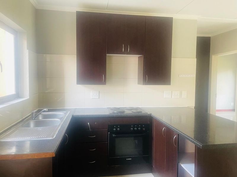 A functional kitchen featuring dark wood cabinetry, granite countertops, a built-in oven and hob, and a stainless steel double sink.