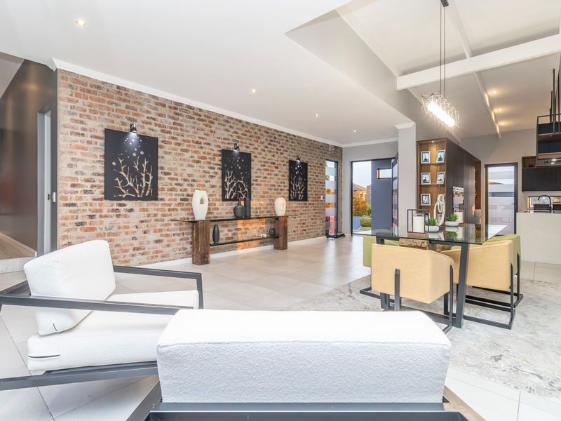 Spacious open-plan living and dining area featuring a striking exposed brick feature wall, vaulted ceilings, and modern tiled flooring throughout.