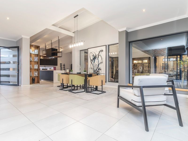 Spacious open-plan living and dining area featuring modern tiled floors, exposed ceiling beams, and seamless flow to the exterior through large glass doors.