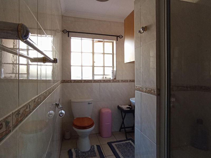 A functional bathroom featuring tiled walls and flooring, a shower enclosure, and a standard toilet suite.