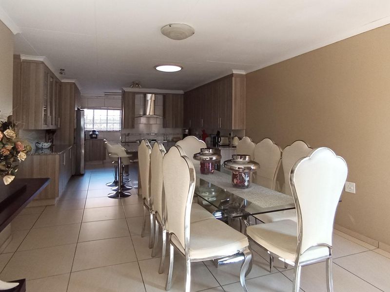 Spacious open-plan kitchen and dining area featuring modern built-in cabinetry, granite countertops, and neutral tiled flooring throughout.