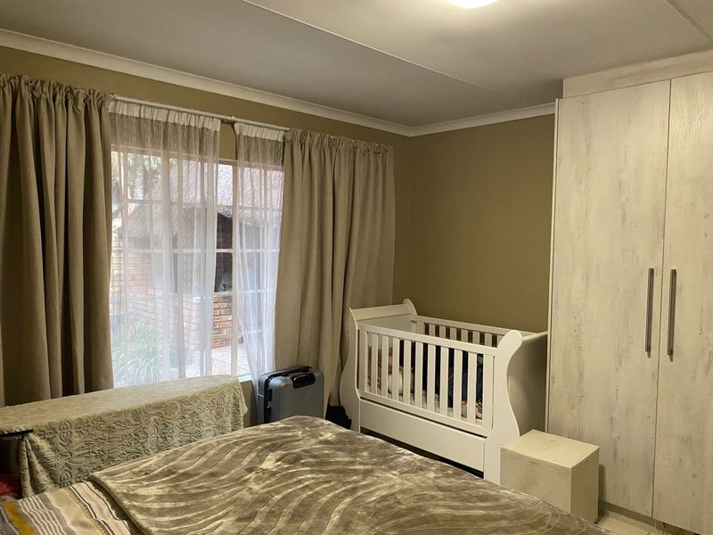 A bedroom featuring a built-in wardrobe and a window with curtains, providing natural light and storage space.