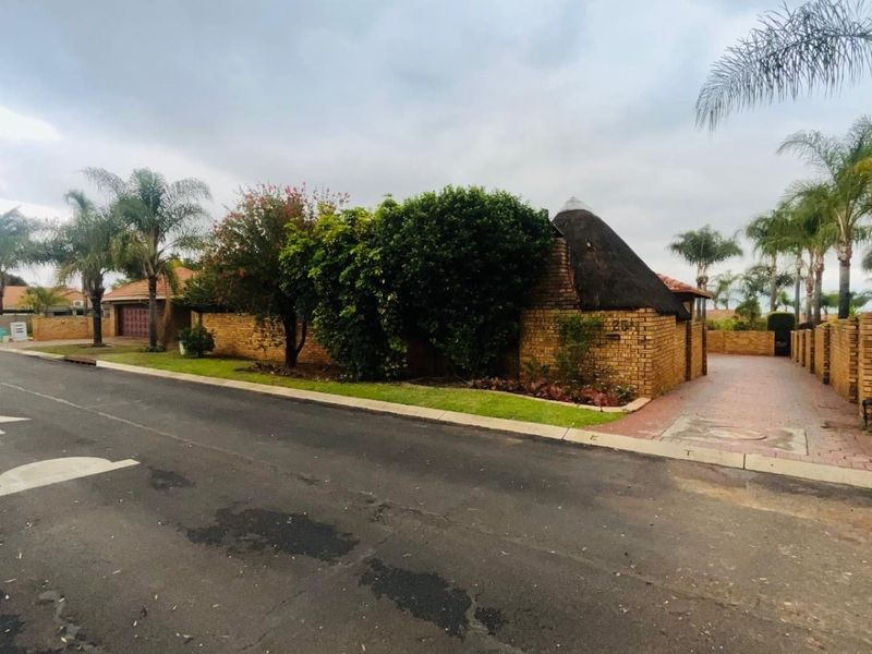 Front exterior view of a townhouse featuring a face brick facade, a distinctive thatched roof section, and a paved driveway.
