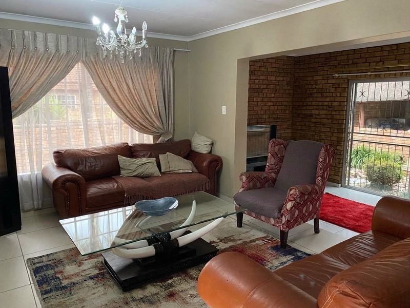 Spacious living room featuring tiled flooring, a built-in fireplace with exposed brick detail, and direct access to an outdoor area through a security gate.