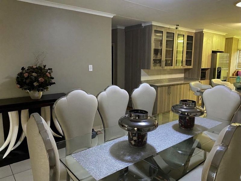 Open-plan dining and kitchen area featuring modern cabinetry, stone countertops, and tiled flooring, creating a cohesive and functional living space.