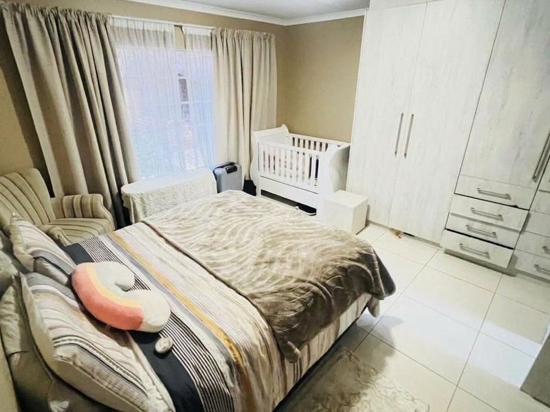 A functional bedroom featuring tiled flooring, neutral wall tones, and ample built-in cupboard storage space.
