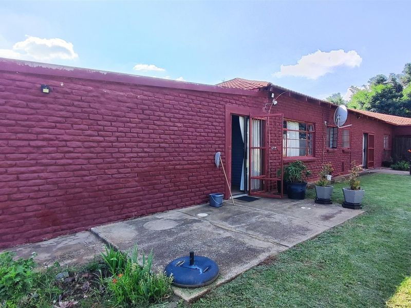 Rear view of the farm property featuring a painted brick facade, concrete patio area, and access to the garden.