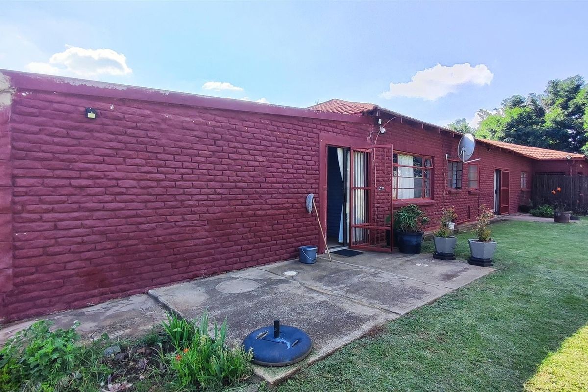 Rear view of the farm property featuring a painted brick facade, concrete patio area, and access to the garden.