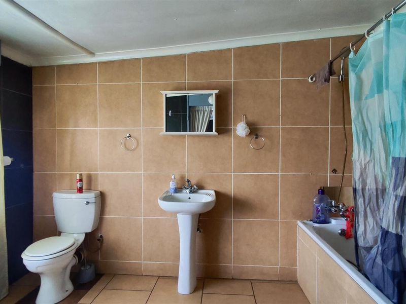 A functional bathroom featuring a pedestal basin, toilet, and bathtub with tiled wall and floor finishes.