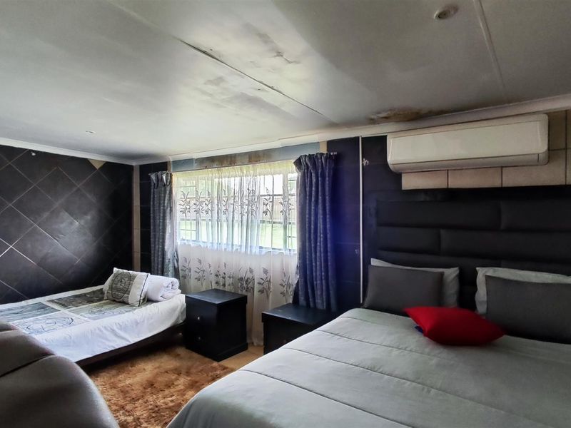 A bedroom featuring a tiled accent wall, split-system air conditioning, and visible ceiling water damage requiring maintenance.
