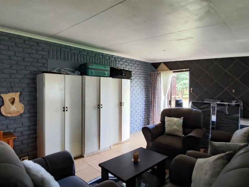Living room featuring exposed brickwork, a tiled feature wall, and built-in storage cupboards with direct access to the exterior.