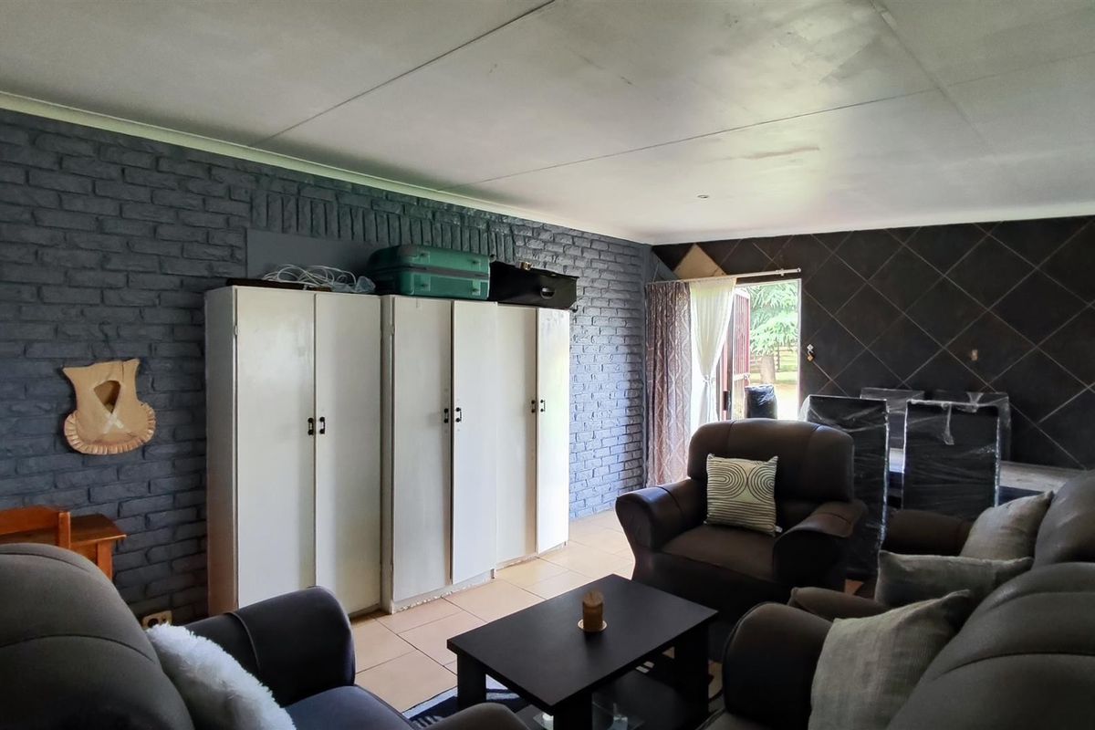 Living room featuring exposed brickwork, a tiled feature wall, and built-in storage cupboards with direct access to the exterior.