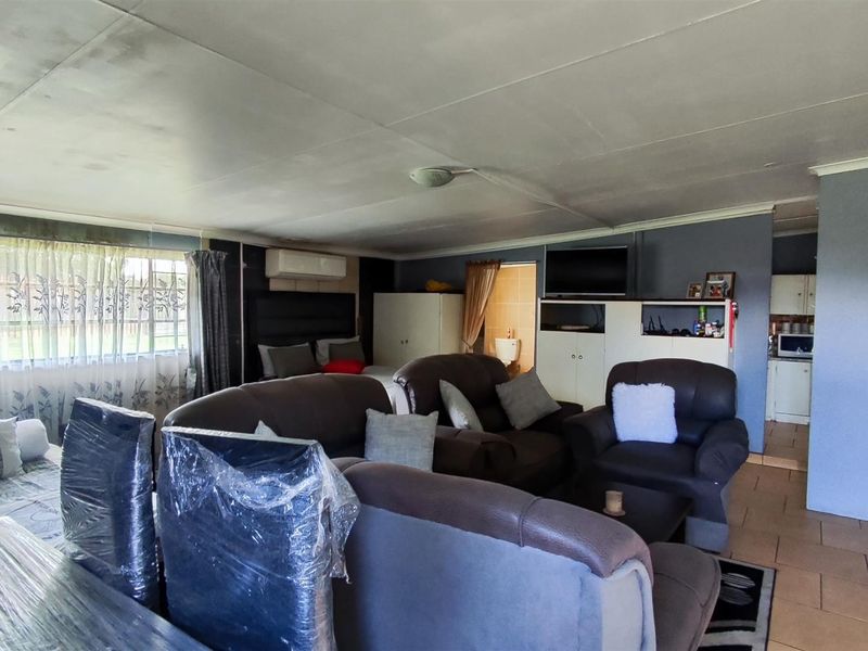 Open-plan living area featuring tiled floors and a split-system air conditioner, with visible ceiling water staining requiring attention.
