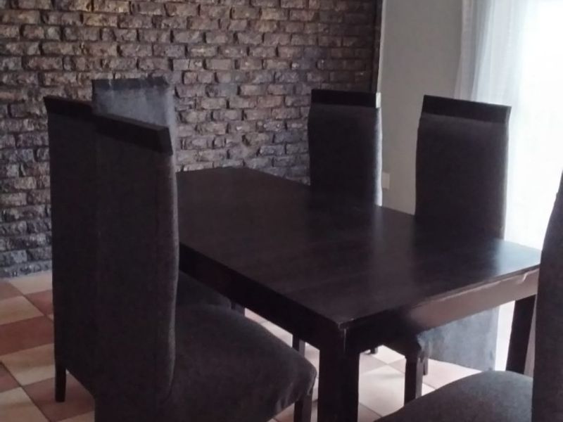 Dining area featuring a rustic exposed brick feature wall and ceramic tile flooring, providing a textured backdrop for the space.