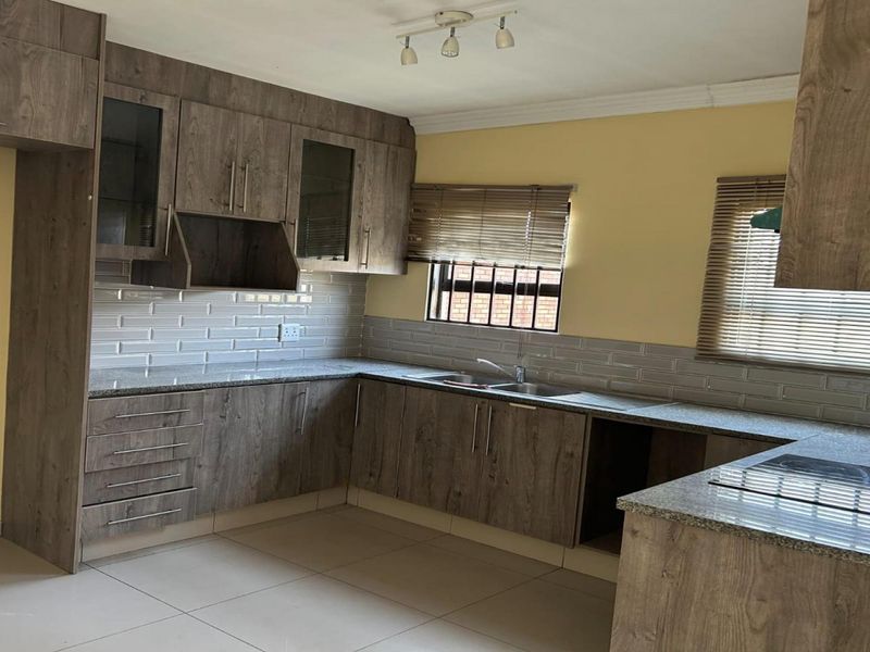 A modern kitchen featuring wood-look cabinetry, granite countertops, subway tile backsplash, and a built-in hob, offering a clean and functional workspace.