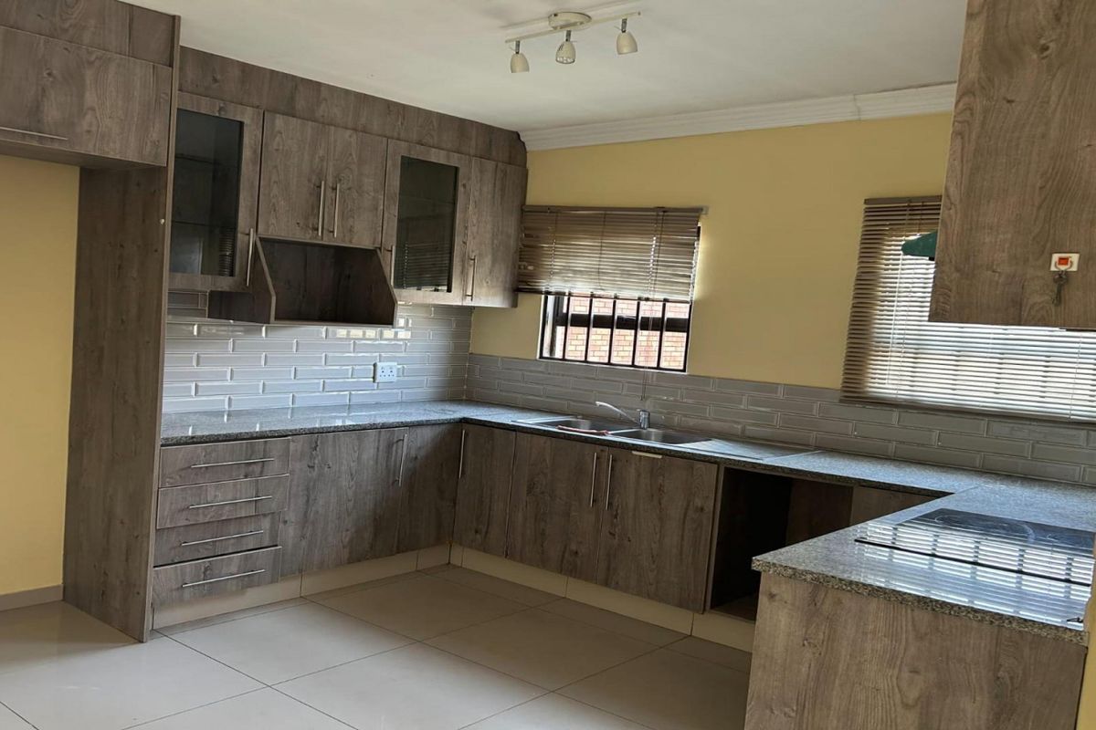 A modern kitchen featuring wood-look cabinetry, granite countertops, subway tile backsplash, and a built-in hob, offering a clean and functional workspace.