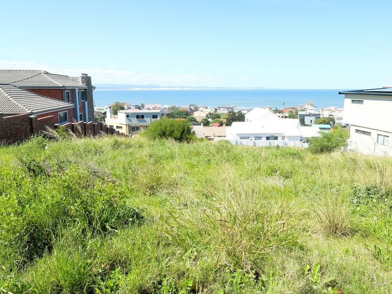A vacant residential plot featuring a gentle slope and expansive views of the surrounding coastal neighborhood and ocean.