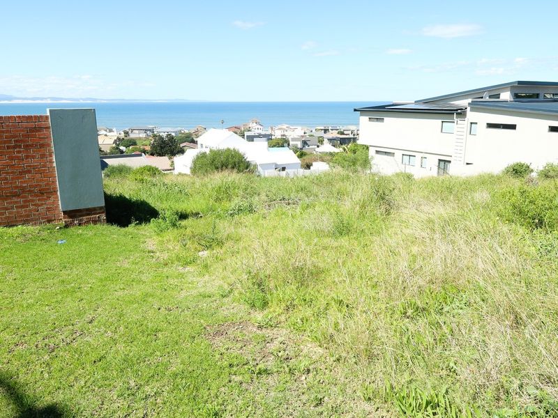 A vacant residential plot featuring an elevated position with scenic coastal and ocean views, bordered by existing residential properties.