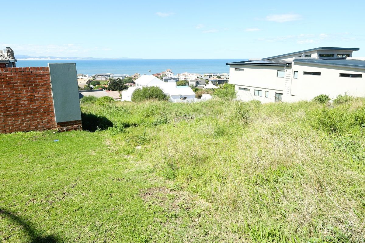 A vacant residential plot featuring an elevated position with scenic coastal and ocean views, bordered by existing residential properties.