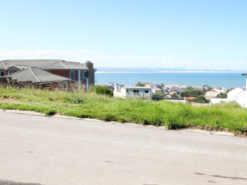 A scenic view overlooking a residential neighborhood with a clear perspective of the coastline and ocean in the distance.