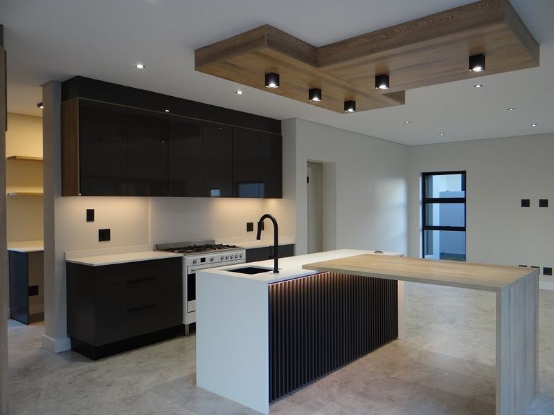 Modern kitchen featuring dark cabinetry, stone countertops, a central island with integrated breakfast bar, and a stylish timber ceiling feature with recessed lighting.