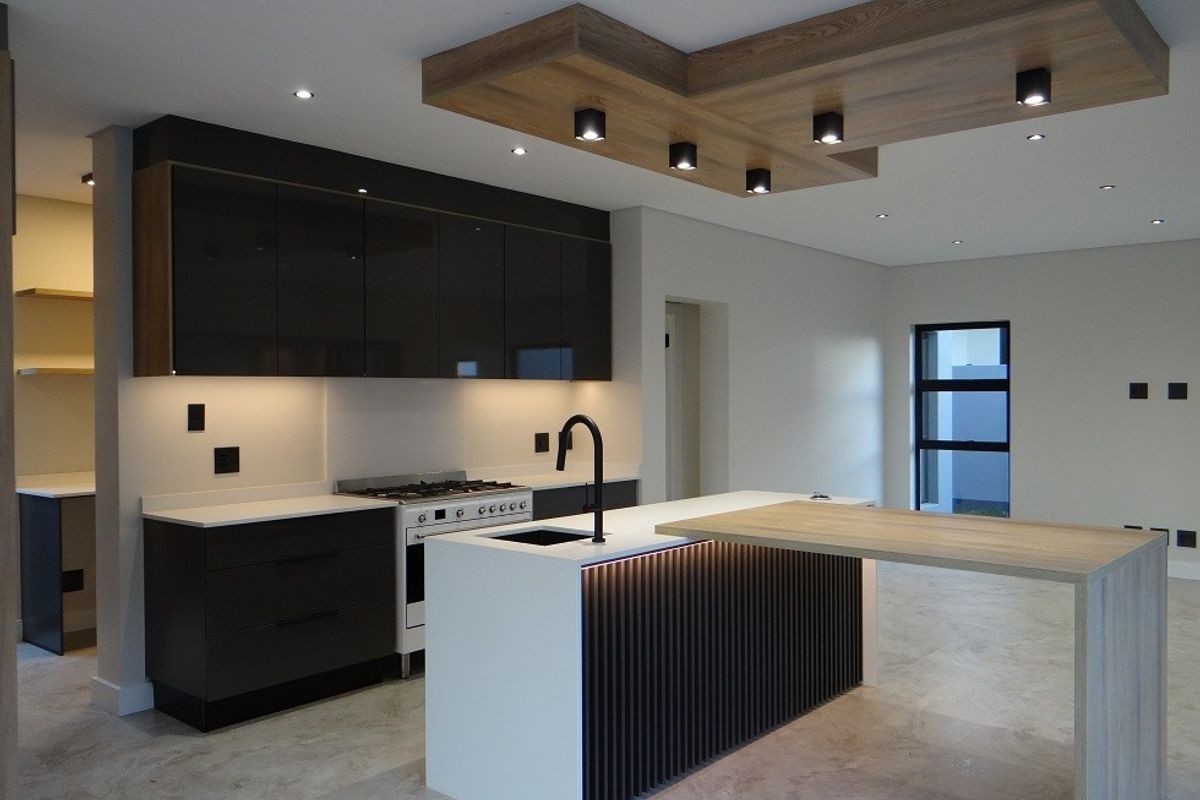 Modern kitchen featuring dark cabinetry, stone countertops, a central island with integrated breakfast bar, and a stylish timber ceiling feature with recessed lighting.