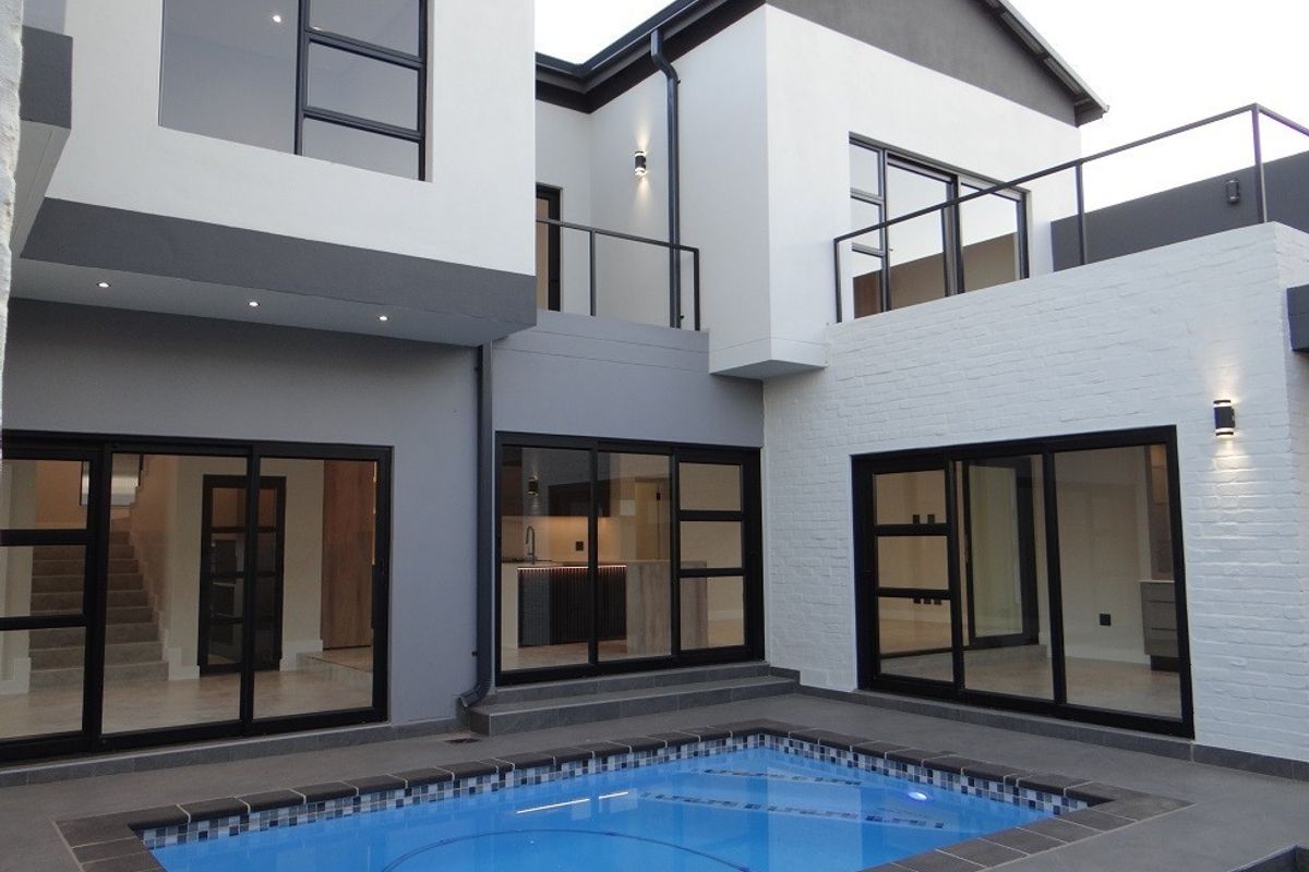 Modern rear exterior view featuring a swimming pool, tiled patio area, and large sliding glass doors providing seamless indoor-outdoor flow to the home.