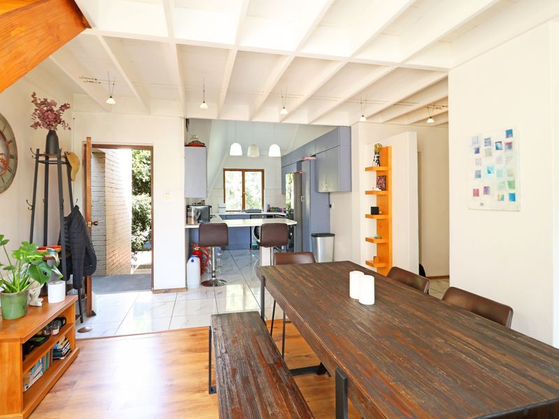 Open-plan living and dining area featuring exposed beam ceilings, a breakfast bar, and a functional kitchen with built-in cabinetry and tiled flooring.