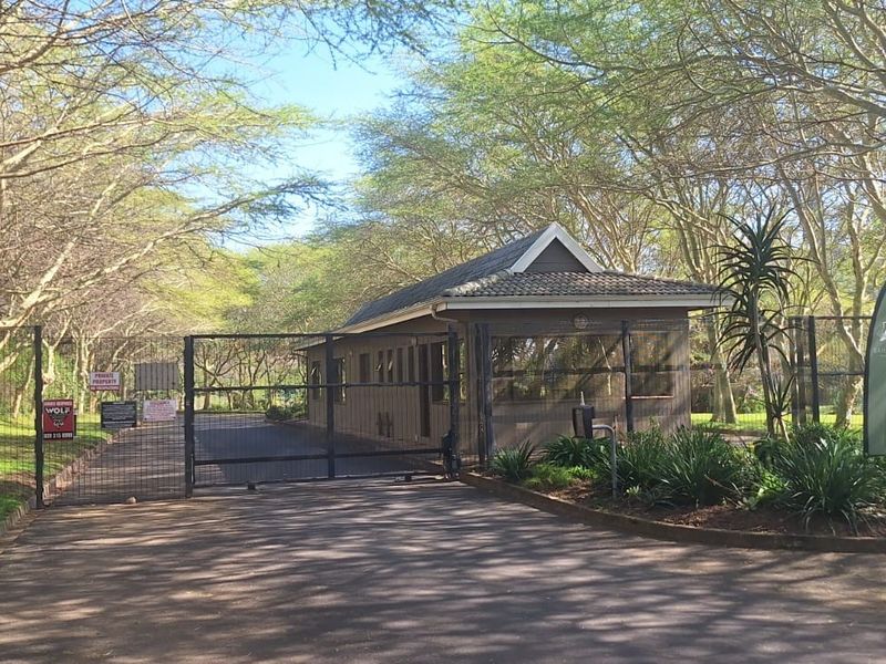 A secure gated entrance to the residential estate featuring a guard house, perimeter fencing, and a well-maintained paved driveway.