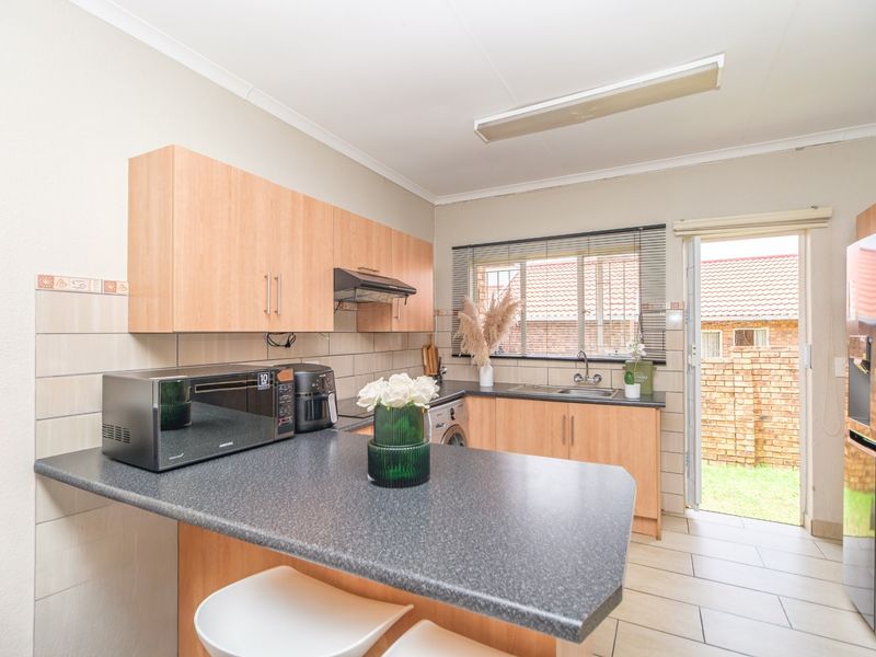 Functional kitchen featuring laminate cabinetry, dark countertops, tiled backsplash, and direct access to the rear garden area.