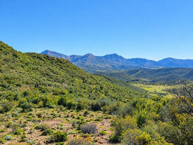A scenic landscape view showcasing the expansive natural terrain, rolling hills, and distant mountain ranges characteristic of the farm property.
