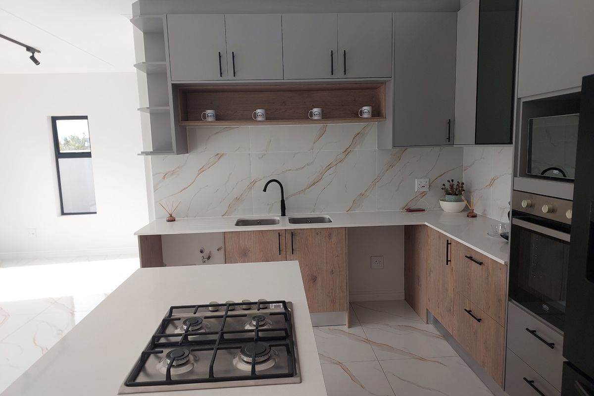 Modern kitchen featuring two-tone cabinetry, stone countertops, marble-look backsplash, integrated gas hob, and built-in oven with high-quality finishes.