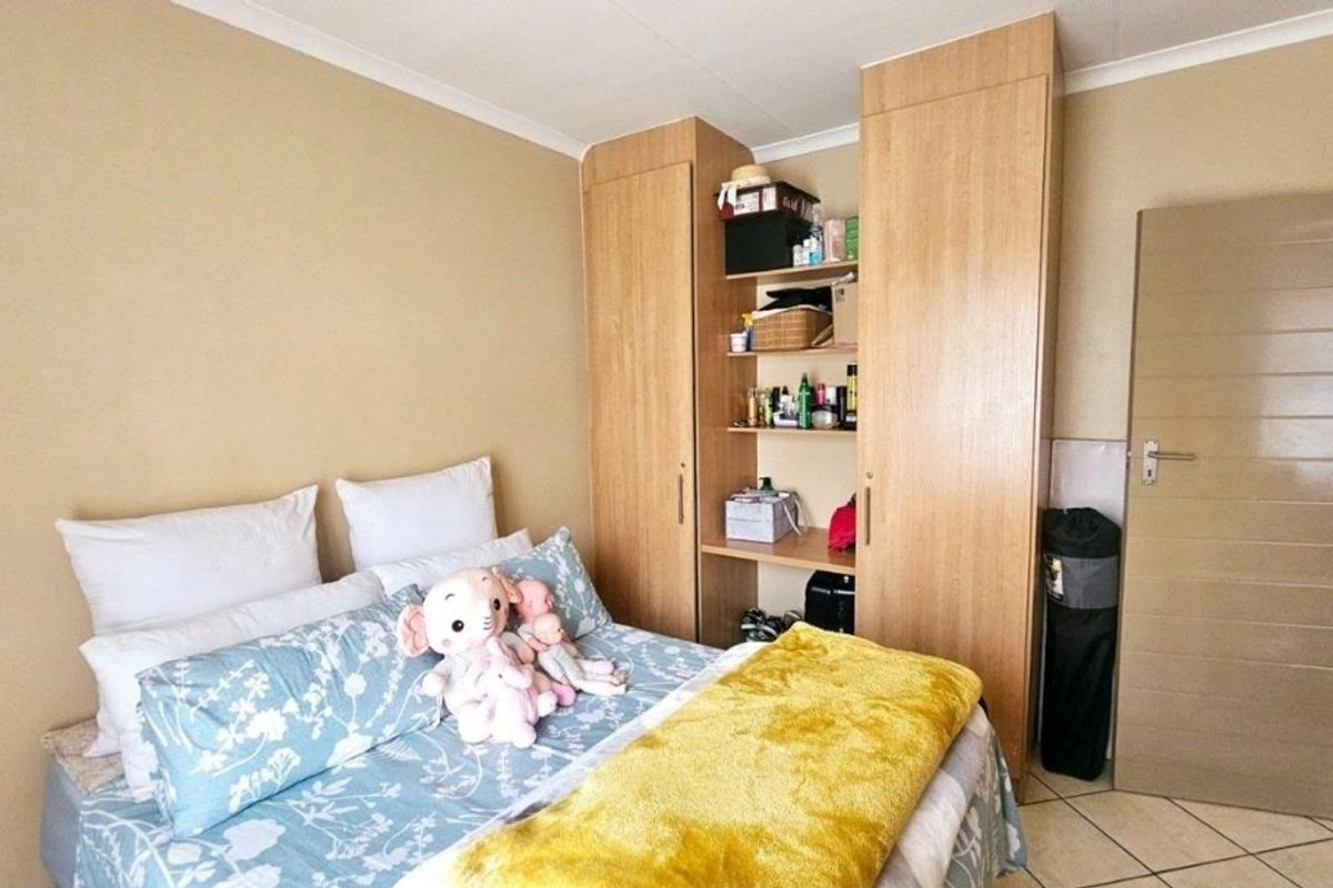A bedroom featuring built-in wooden cupboards and tiled flooring, providing functional storage space within the apartment.